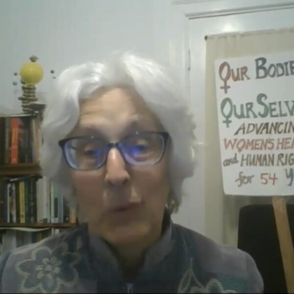 A screenshot of Judy from the event. She is sitting in front of a book shelf and a sign that reads "Our Bodies Ourselves." She has short white hair and is wearing glasses. Below in black is the following text: "Our Bodies Ourselves: Half a Century of Health & Sexuality Education and Activism"