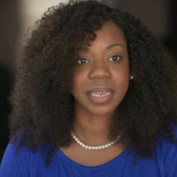 A screenshot of Beverly Gooden from the documentary. She is a Black woman with curly hair wearing a blue top and pearl necklace.