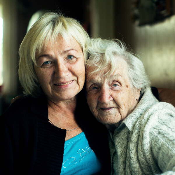 An elderly mother and her older adult daughter pose for a picture together