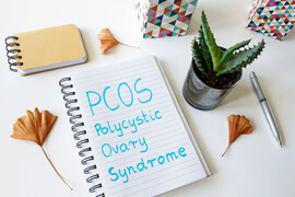 A notebook on a white table with the words "PCOS Polycystic Ovary Syndrome" written on it