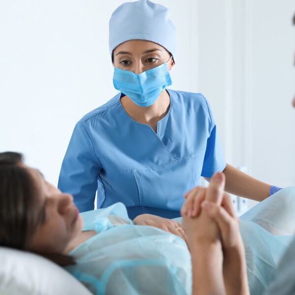 Woman giving child birth in maternity hospital, focus on midwife