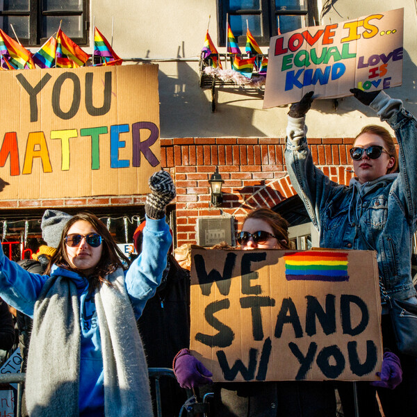 Activists stand in front of Stonewall Inn with signs that read "You Matter," "We Stand w/ You," "Love is... equal, kind, love is love."