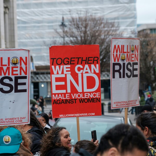 People in London hold signs that read "Together We Can End Male Violence Against Women" and "Million Women Rise."