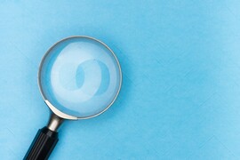 Magnifying glass in front of blue background.