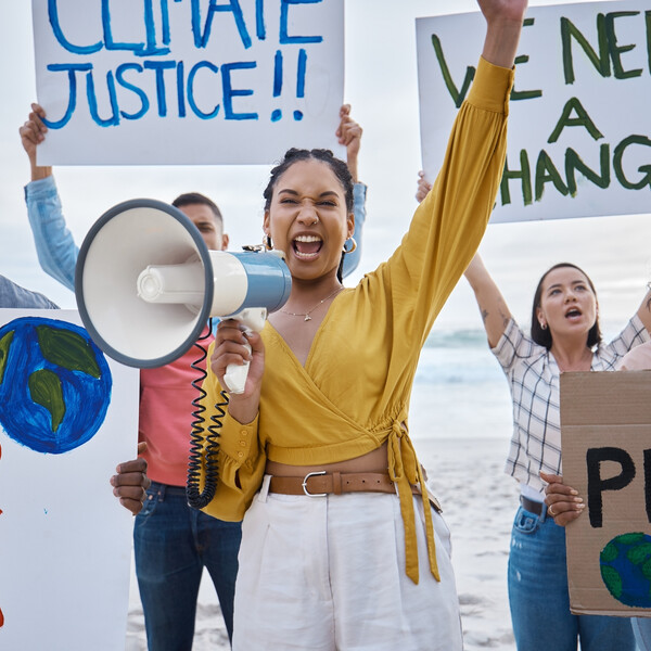 A protest on a beach with a woman standing in the middle with megaphone