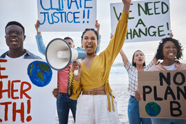 A protest on a beach with a woman standing in the middle with megaphone