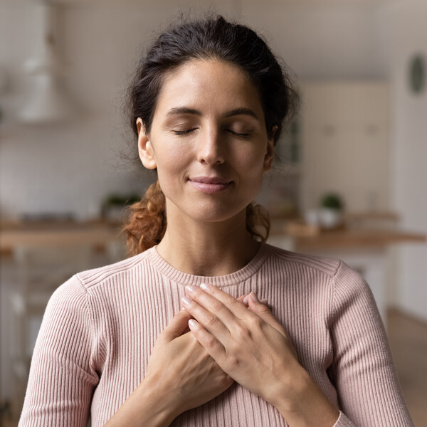 A woman with her hands on her chest as though meditating