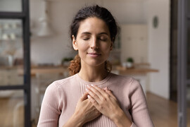 A woman with her hands on her chest as though meditating