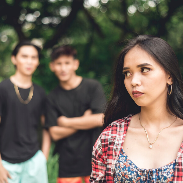 A woman looks over her shoulder at two men who appear to be talking about her