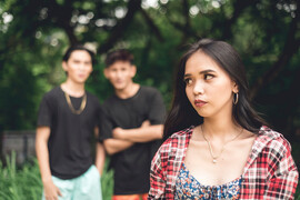 A woman looks over her shoulder at two men who appear to be talking about her