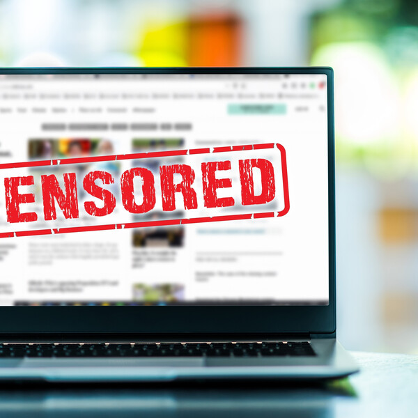 A laptop on a table with the word "Censored" in red on the screen