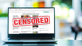 A laptop on a table with the word "Censored" in red on the screen