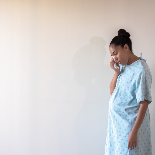 A woman in a hospital gown cries in a hallway