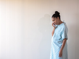 A woman in a hospital gown cries in a hallway