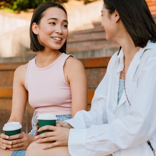 Two Asian women sit outside chatting