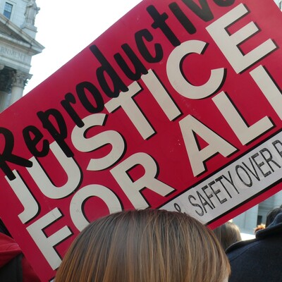 A red sign that says, "Reproductive Justice for All"