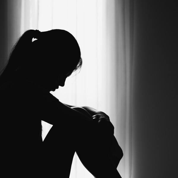 A woman sitting in a shadow in front of a window