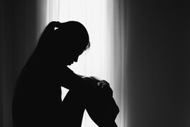 A woman sitting in a shadow in front of a window