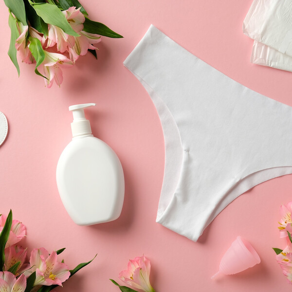 A pink background with white period products and pink flowers
