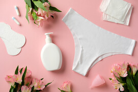 A pink background with white period products and pink flowers