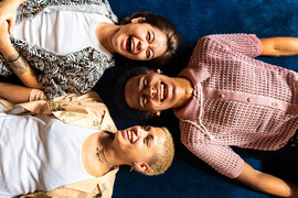 Three queer people lay on the floor laughing together