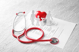A white table with a family history form, a stethoscope, and a paper cutout of a family around a heart