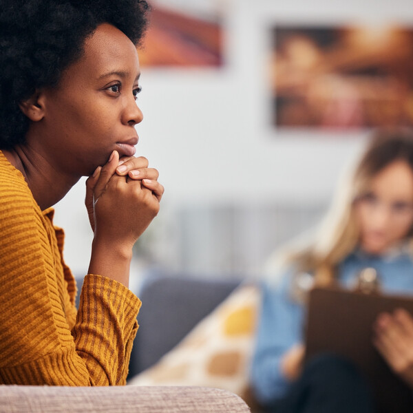 A Black woman with an afro sits in front of a therapist