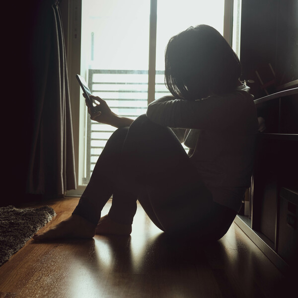 A woman sitting on the floor looking at her phone