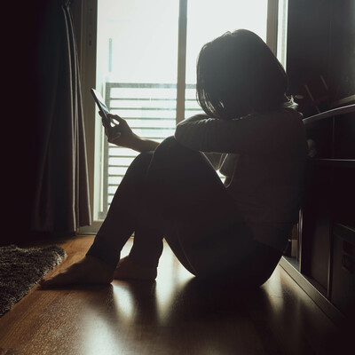 A woman sitting on the floor looking at her phone