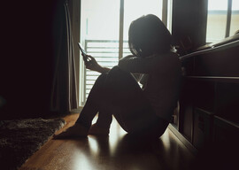 A woman sitting on the floor looking at her phone