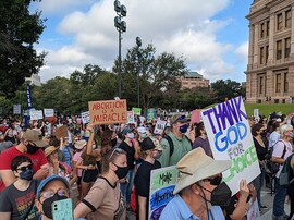 Crowd at a rally against SB 8 at the Texas Capitol with signs reading "abortion is a miracle" and "thank God for choice"