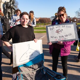 Two protestors at an anti-abortion protest with signs that read: "We Won't Go Back" and "Fuck with Our Eggs And We'll Break Your Legs"