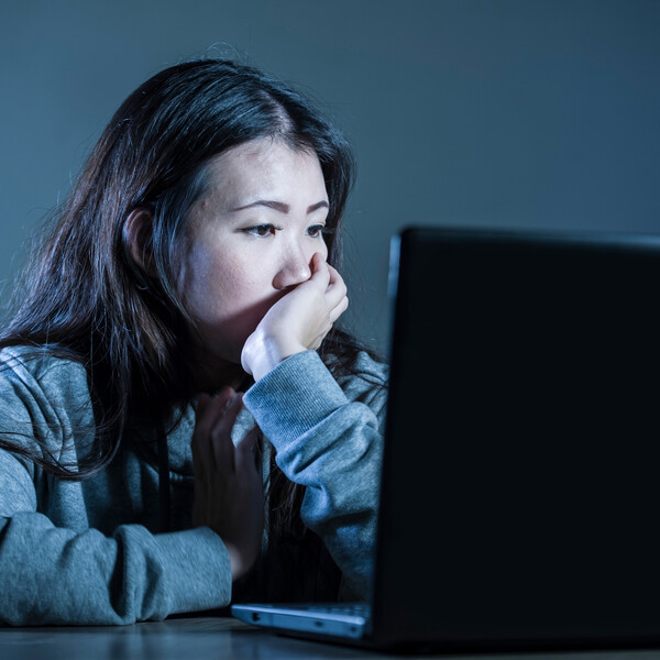 An Asian woman stares at a computer