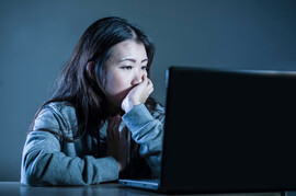 An Asian woman stares at a computer