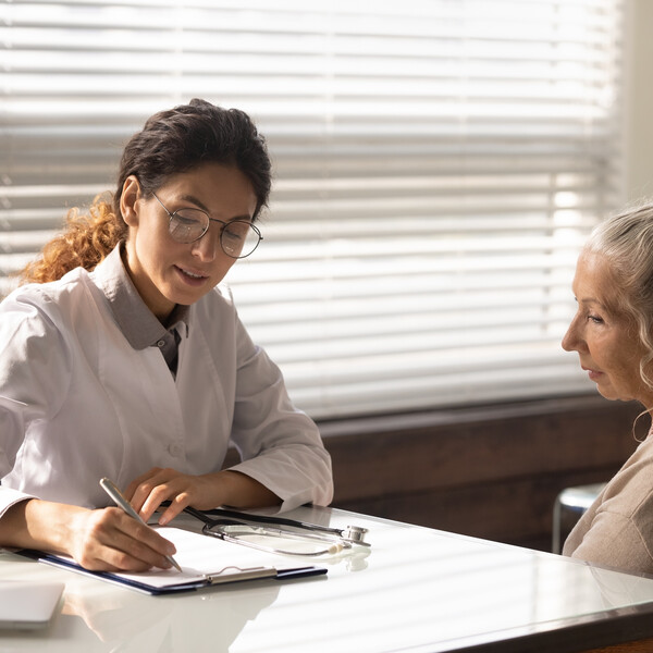 An older woman sits with a doctor