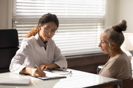 An older woman sits with a doctor