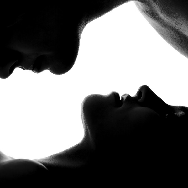 A man and woman's faces cast in a dark light against a white background