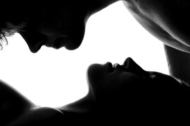 A man and woman's faces cast in a dark light against a white background