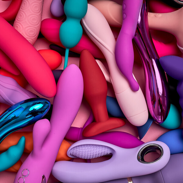 Pink table with varying types of sex toys in varying colors