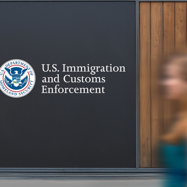 The U.S. Immigration and Customs Enforcement building with a woman passing by