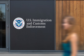 The U.S. Immigration and Customs Enforcement building with a woman passing by