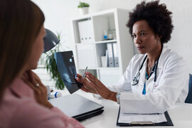 A woman sits in front of her doctor to discuss her mamogram