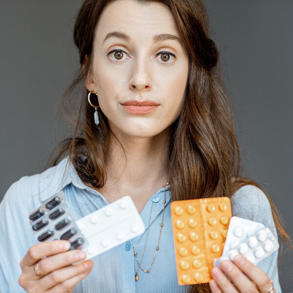 A woman with a straight face holding birth control pills