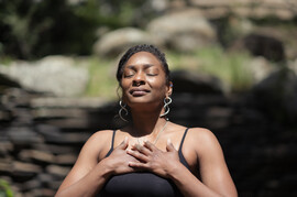Genderqueer/nonbinary person meditating outside
