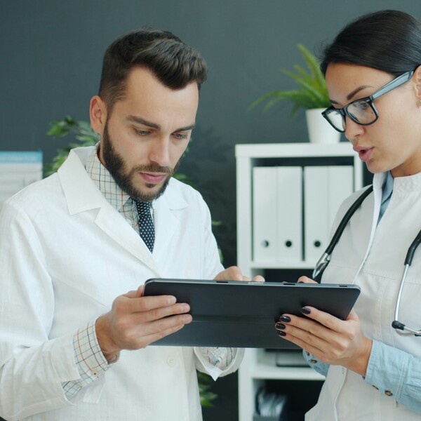 Two doctors talk while looking at an iPad