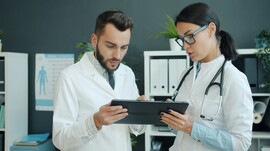 Two doctors talk while looking at an iPad