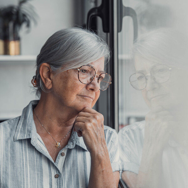 An older woman looks out a window
