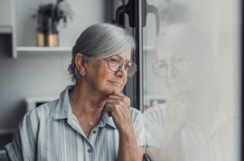 An older woman looks out a window