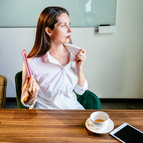 A woman sitting at a desk fanning herself