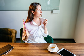 A woman sitting at a desk fanning herself